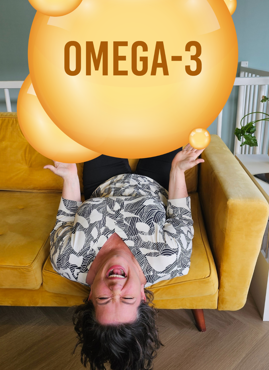 Cecilia van Stressst ondersteboven op bank, bedolven onder grote omega 3 bol als symbool voor hoeveel omega 3 je écht nodig hebt